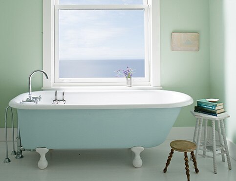 Serene light green bathroom with clawfoot tub.
