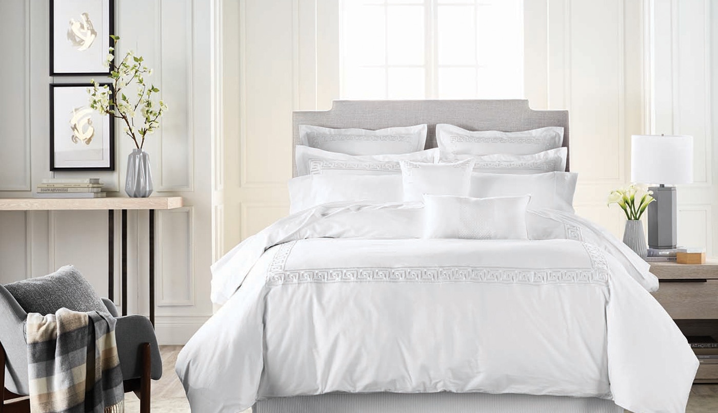 The palest gray walls flatter a bedroom with fluffy white bedding.