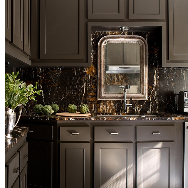 Des armoires d’un brun riche, un dosseret en marbre brun et un miroir décoratif créent un somptueux décor de cuisine.