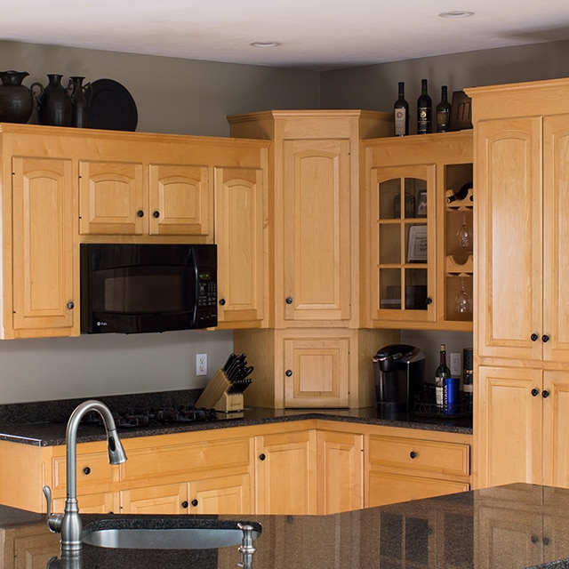 A Kitchen with wood cabinets, black countertops and appliances before a makeover.