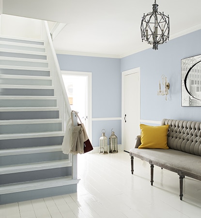 Light blue and gray foyer opens to a staircase with alternate gray risers and white trim.