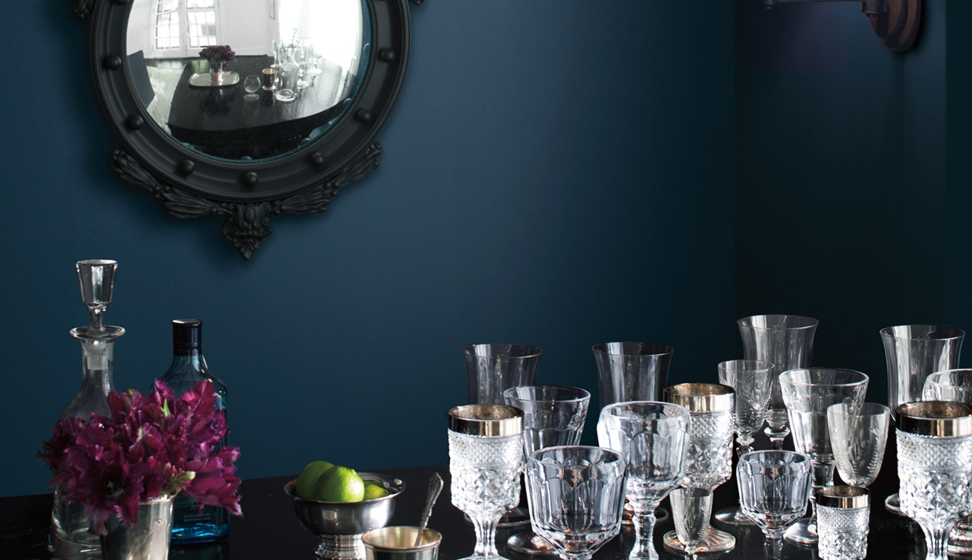 Le mur bleu foncé de cette salle à manger met en valeur ces verres ornés posés sur une table.