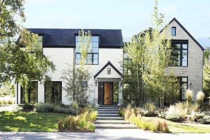 Une maison moderne de style campagnard arborant une façade blanche et une moulure extérieure noire