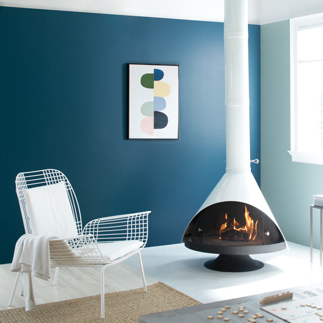 Un salon intime où trône une cheminée de style rétro présente de murs peints en bleu