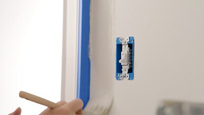 Un entrepreneur en peinture découpe un interrupteur