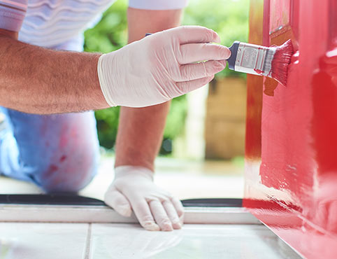 A Benjamin Moore painting contractor paints a red front door