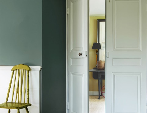 A hallway with white painted doors and a green chair