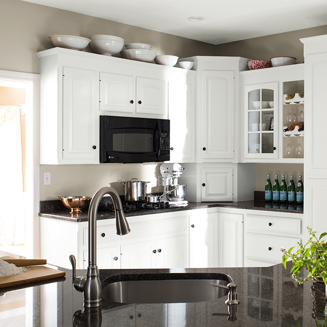 The same kitchen after a makeover, with fresh white-painted cabinets, black countertops and appliances.