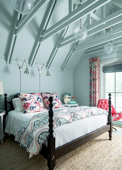Vibrant blue bedroom with matching industrial ceiling including a large bed with printed bedding.