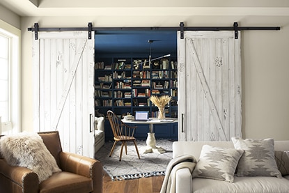 Sliding barn doors open to striking built-in blue bookshelf painted in Champion Cobalt 2061-20.