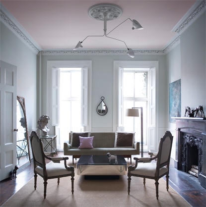 Un salon bleu-gris se distingue par son plafond rose pâle. 