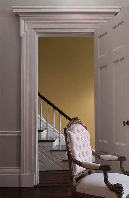 A living room in light gray features a door opening to a yellow-painted foyer.