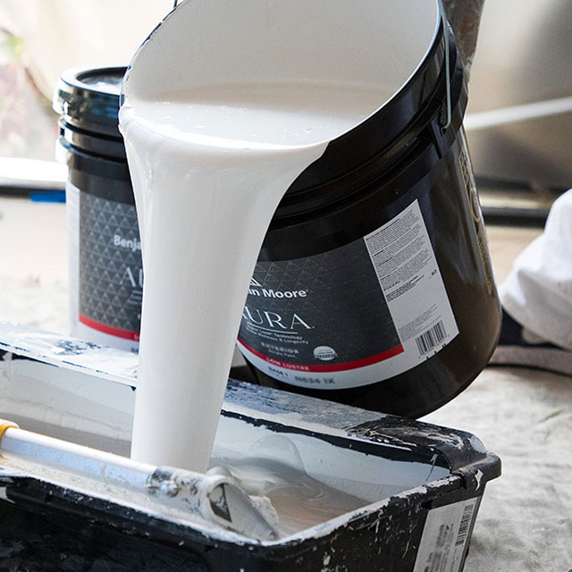 A Painting Contractor pouring AURA® Exterior Paint into a tray.