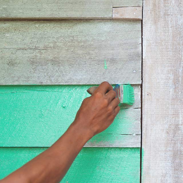 A wood surface being painted in a teal colour