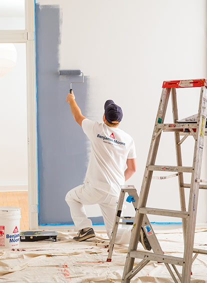 A painting contractor enjoys the ideal application properties of Gennex®-engineered paint while painting a wall.